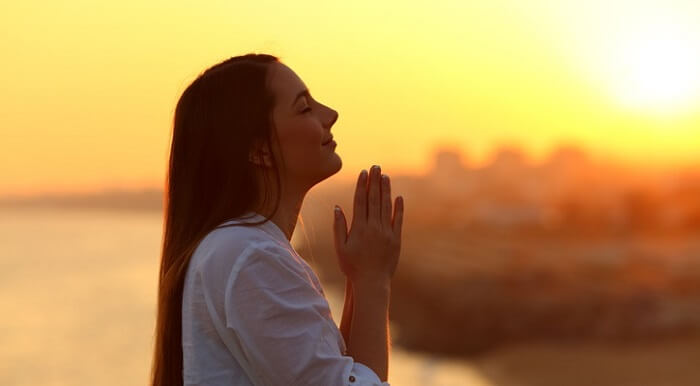Profile of a happy woman praying at sunset