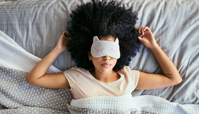 young african-american woman in bed with sleeping mask on