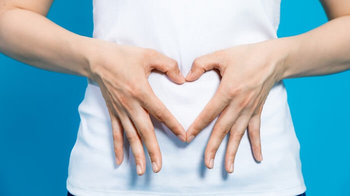 woman making heart shape over stomach with hands
