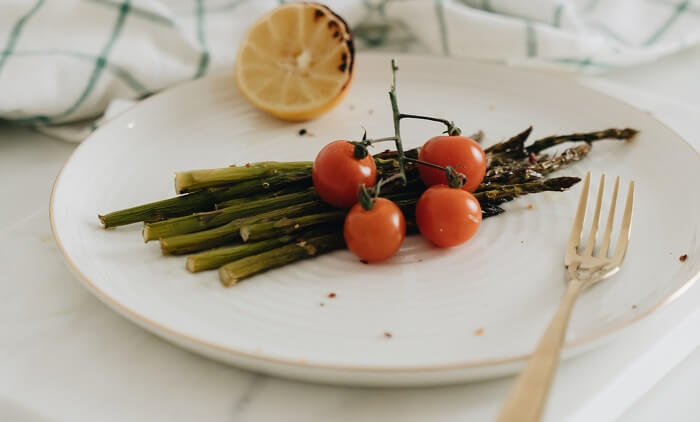 asparagus and tomatoes and lemon on plate