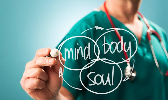 holistic health concept - practitioner writing mind body spirit on board