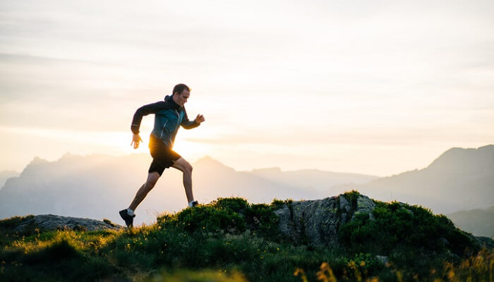 man jogging on mountaintop at sunrise